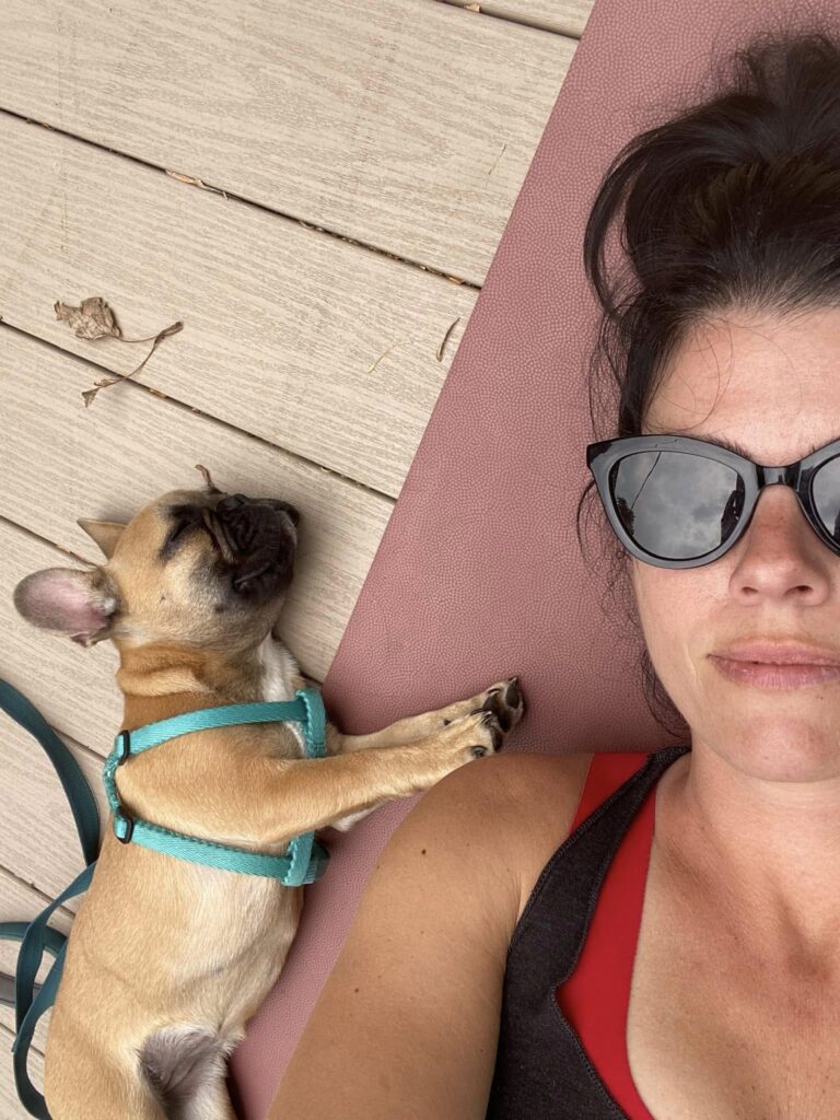 Kristen and Baby Vida on a yoga mat outside.